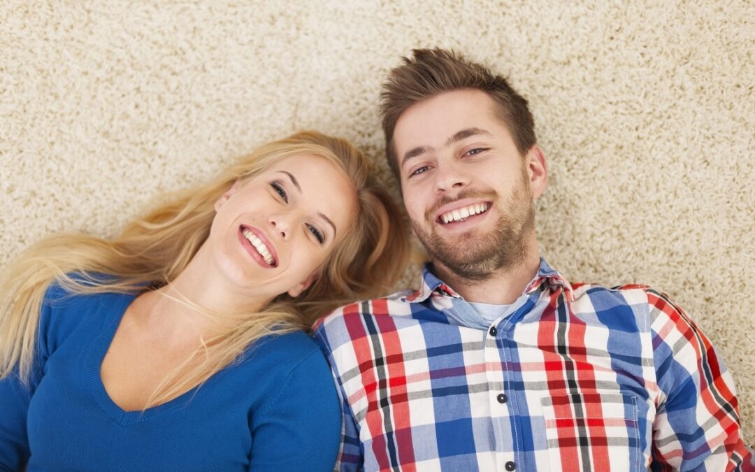 Portrait of happy couple lying down on carpet