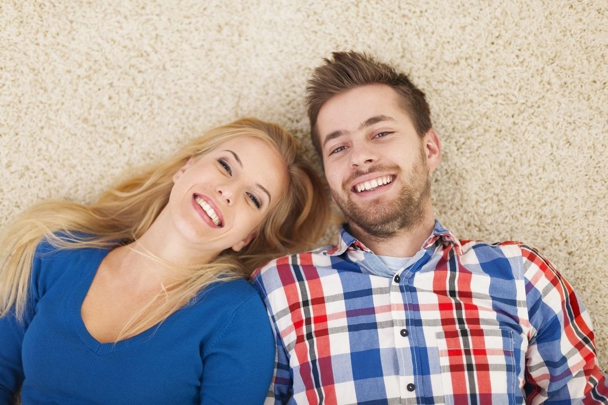 Portrait of happy couple lying down on carpet